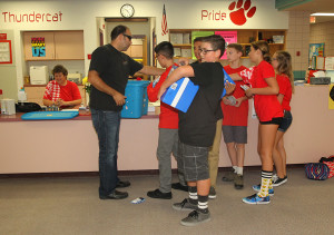 Chad Nelson hands supplies to students at Thunderbolt Middle School Friday morning. Jillian Danielson/RiverScene 