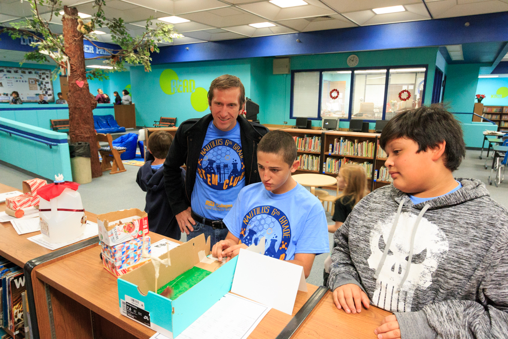 Dr. Ryan Jeannette, ASU Professor and volunteer judge, looks on as s Nautilus STEM Club student plays with one of the Elf Engineering designed games. 
