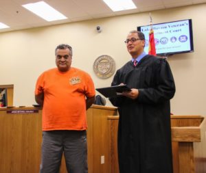 Graduate Carlos Rodriguez receives certificate from Judge Kalauli. Rick Powell/RiverScene 