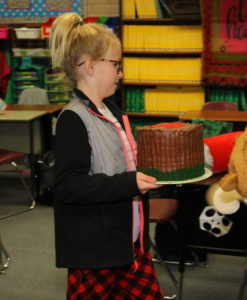 Kadenz Kathers carries a cake she made for the Taste of Sixth Grade. Jillian Danielson/RiverScene 